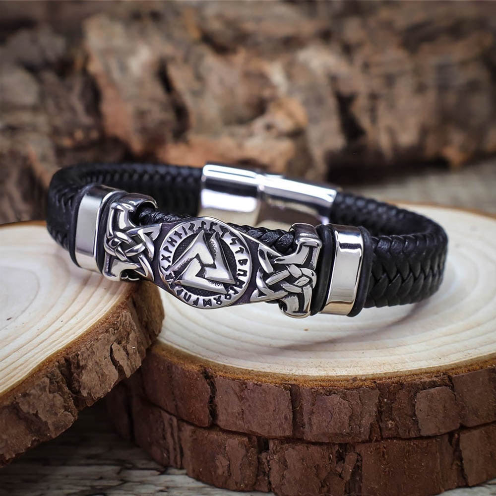 Black leather bracelet with silver metal clasp on wooden surface