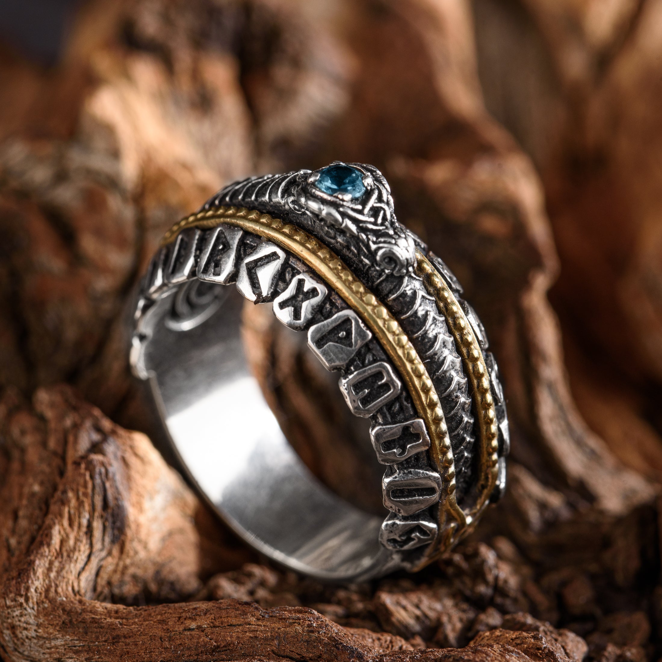 Silver and gold ring with a blue gemstone on a wooden background