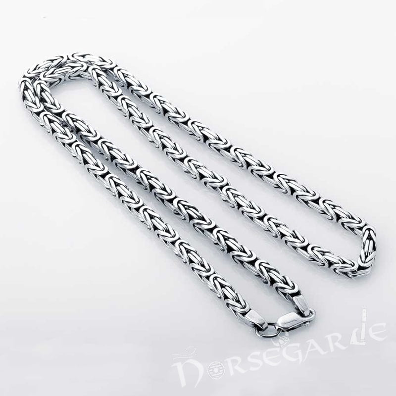 Silver chain necklace on a light gray background.