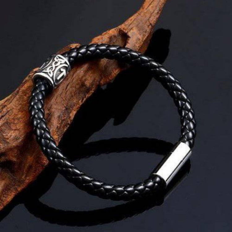 Black braided leather bracelet with silver clasp on a dark background