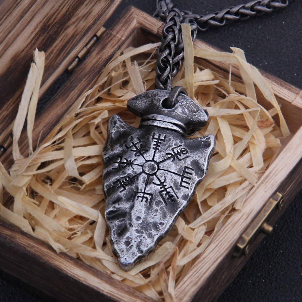 A runic hammered arrowhead pendant displayed on a wooden box with a stainless steel chain necklace.